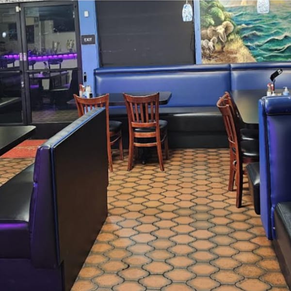 Interior of Los Cebollines Grill with blue booths, wooden chairs, and a mural of elephants by the ocean.