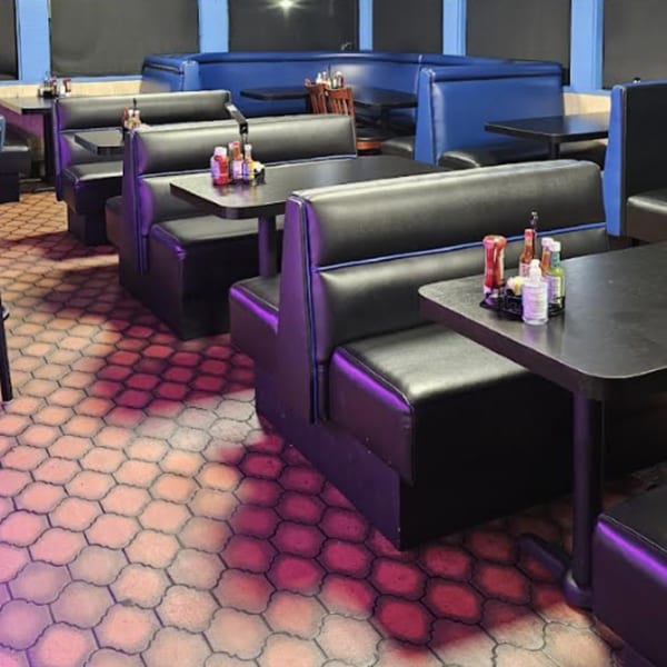Interior of Los Cebollines Grill with black booths, blue accents, and tables with condiments.
