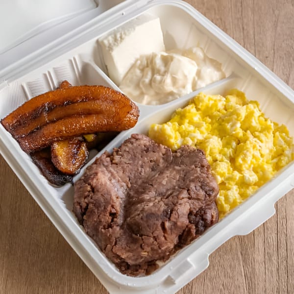 Salvadoran breakfast with fried plantains, refried beans, scrambled eggs, and cheese in a takeout container.