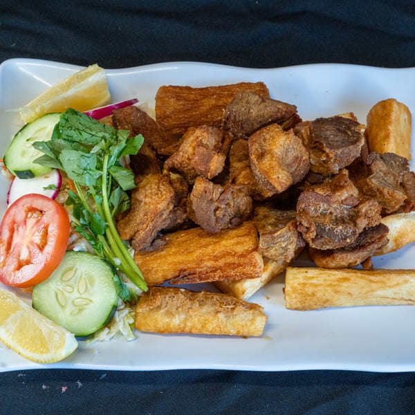 Los Cebollines Grill's fried pork and yuca, served with fresh salad and lemon wedges.