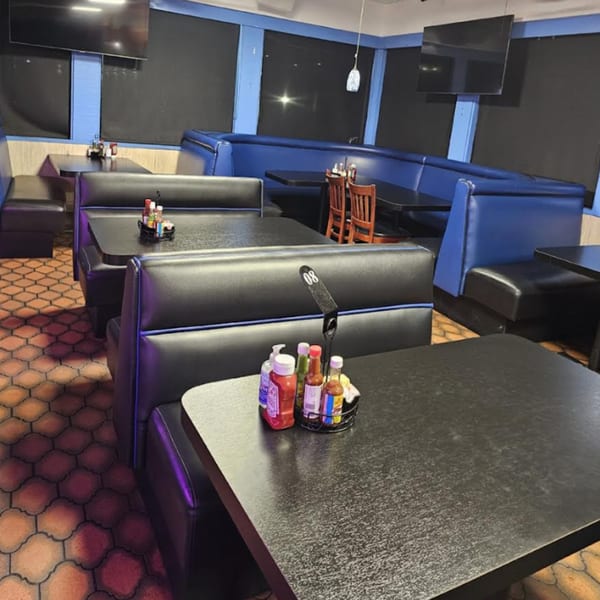 Interior of Los Cebollines Grill with black booths, blue accents, dark tables, and patterned floor.